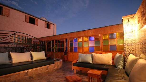 An outdoor seating area with a wooden bench, a sofa, and a small table. - Riad les Chtis d'Agadir (Agadir)