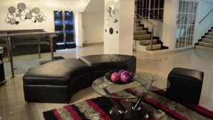 A modern living room with a glass coffee table, black leather sofas, and a decorative wall art piece. - Hotel Calima Real (Cali)