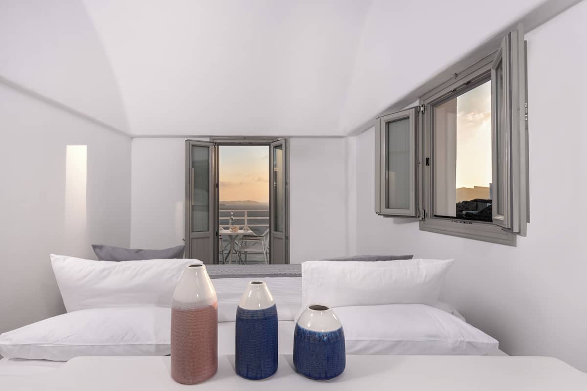 A modern hotel room with a large bed, white linens, and three decorative vases.