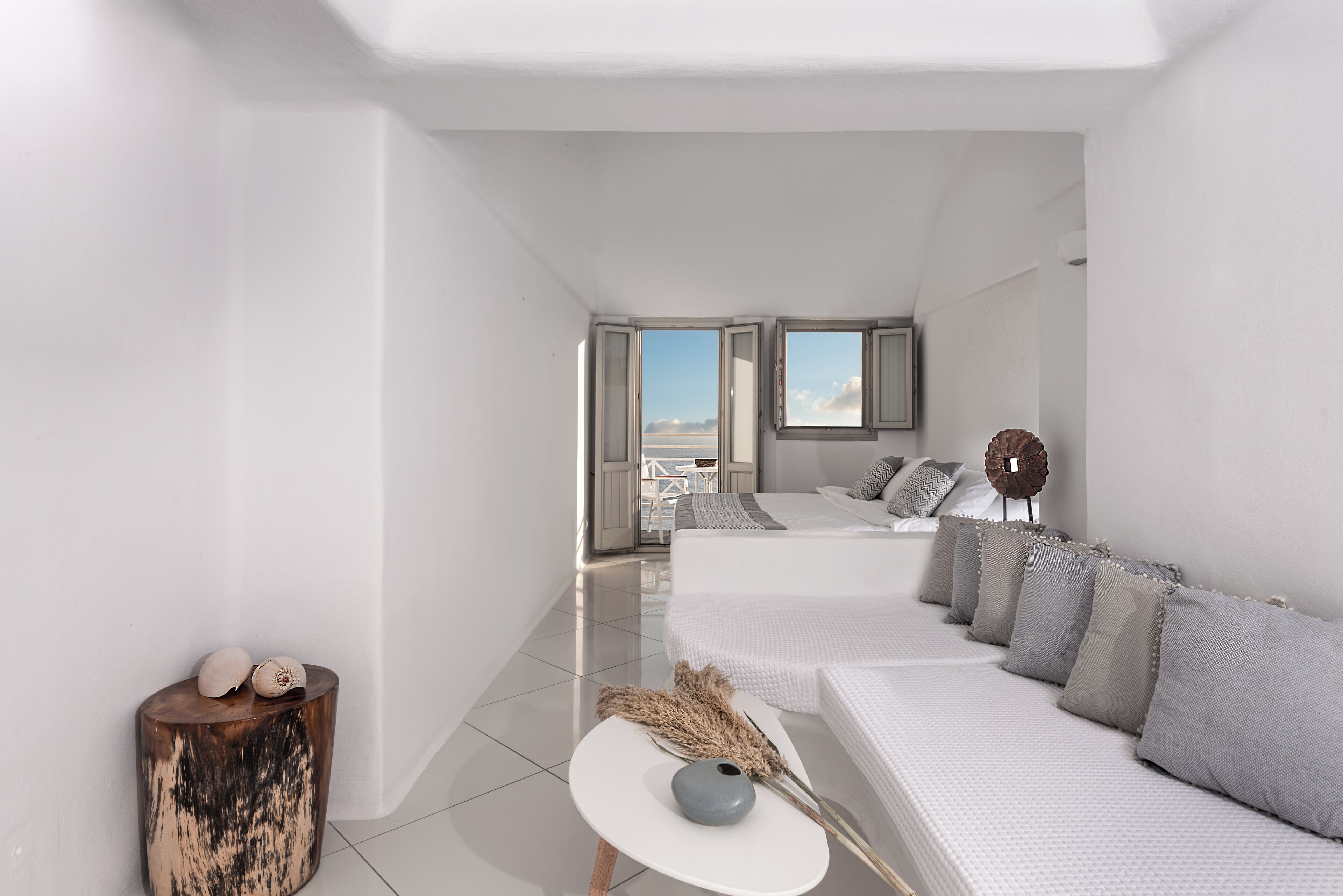 Une chambre à coucher moderne et minimaliste, dotée d’un grand lit, d’une petite table de chevet et offrant une vue sur l’extérieur.