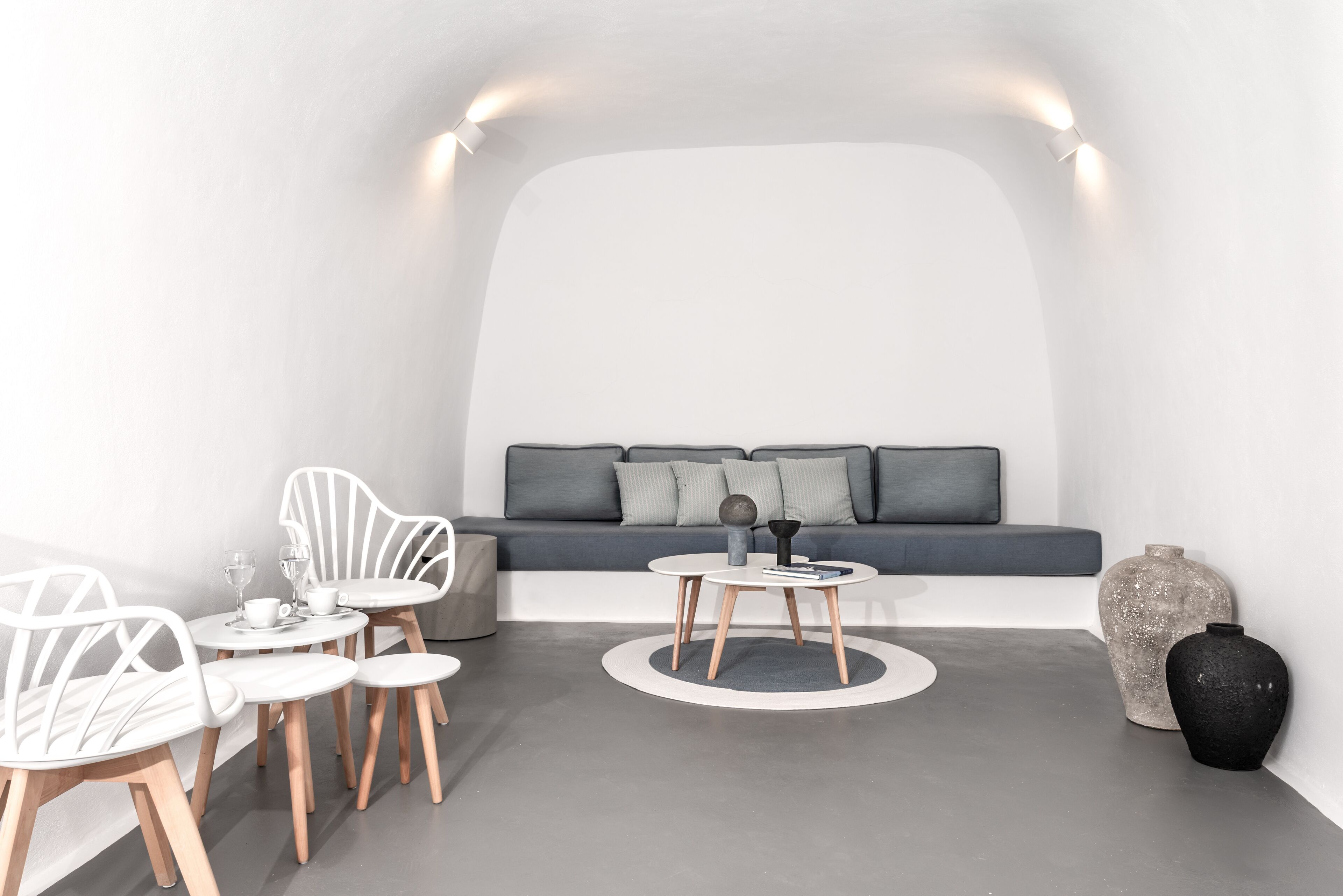 Une pièce moderne et minimaliste, avec un canapé, deux petites tables et des chaises blanches.