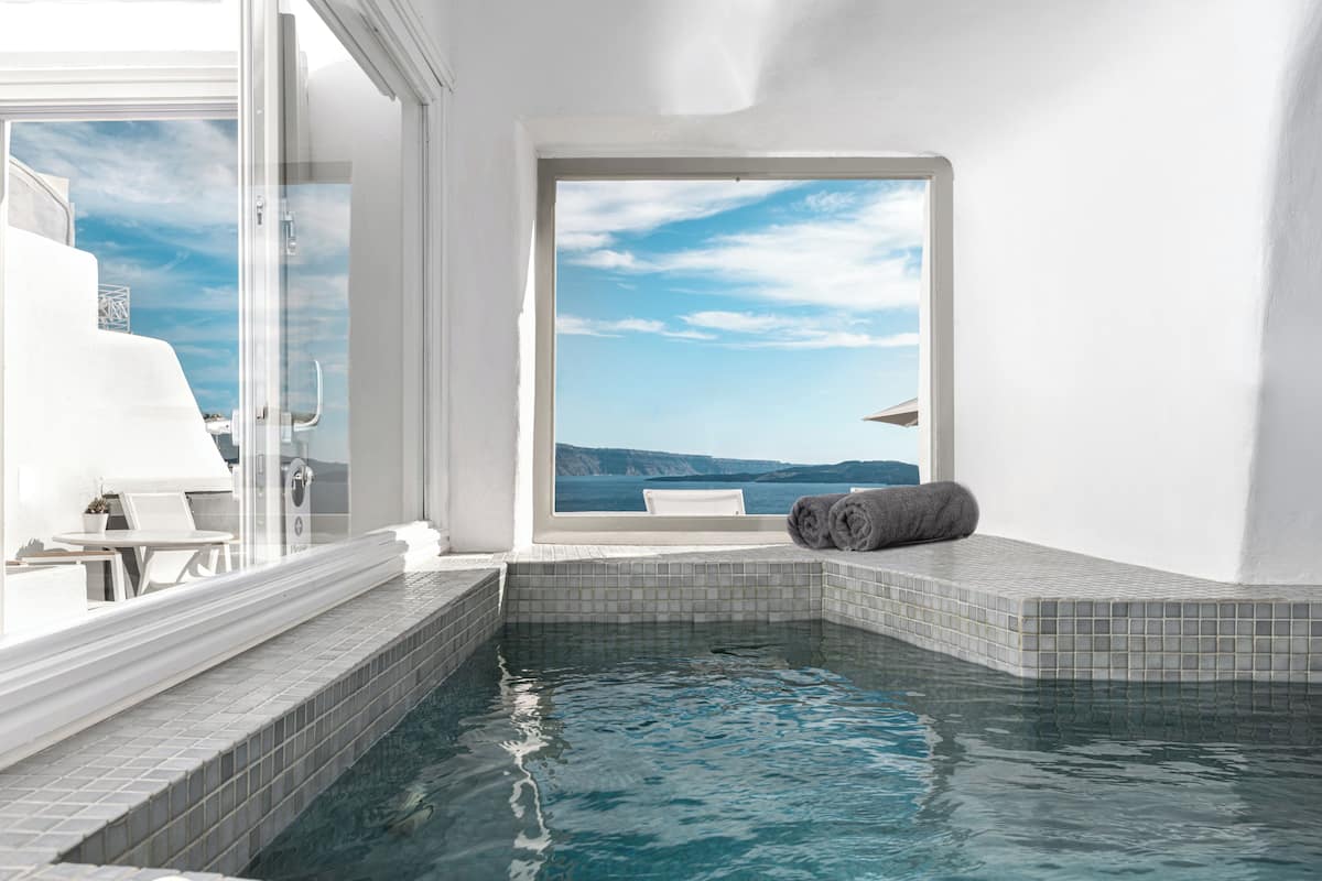 A modern indoor pool with a clear view of the sea and a white interior.