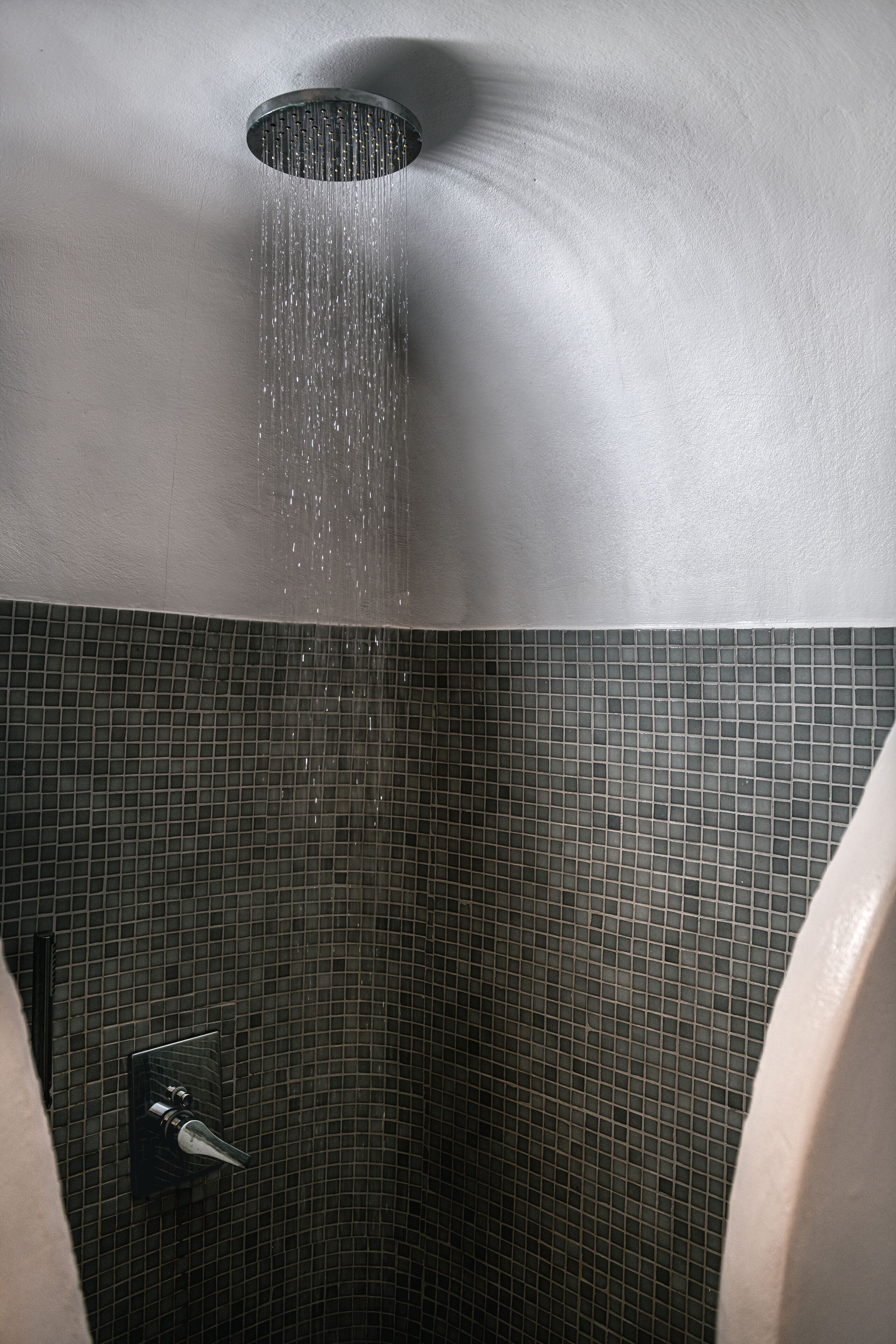 A shower with a curved ceiling and a tiled wall.