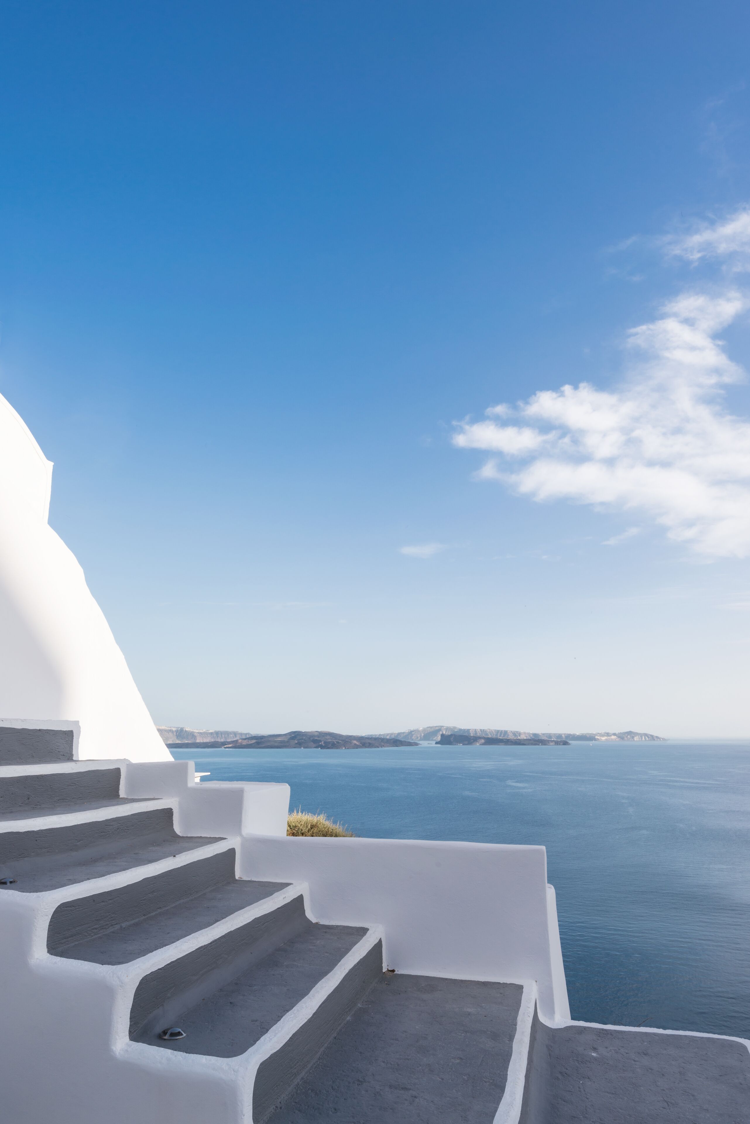 A white staircase leading to a scenic overlook with a view of the sea and distant landforms.