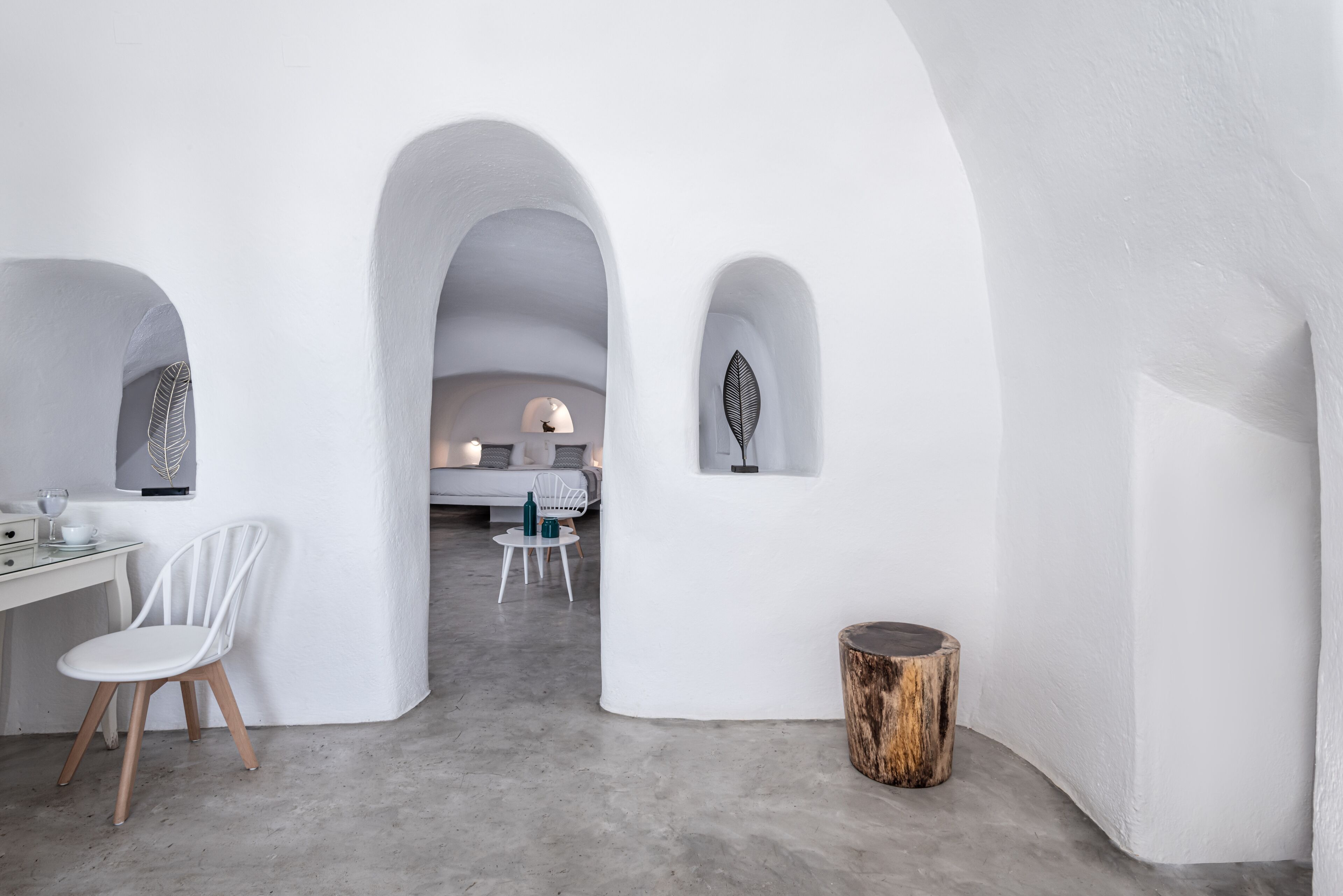 Un intérieur moderne avec des murs blancs, une chaise blanche, une table en bois et un petit tabouret en bois.