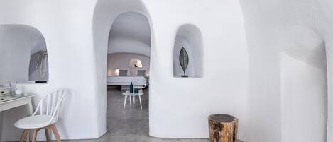 A modern interior with white walls, a white chair, a wooden table, and a small wooden stool.