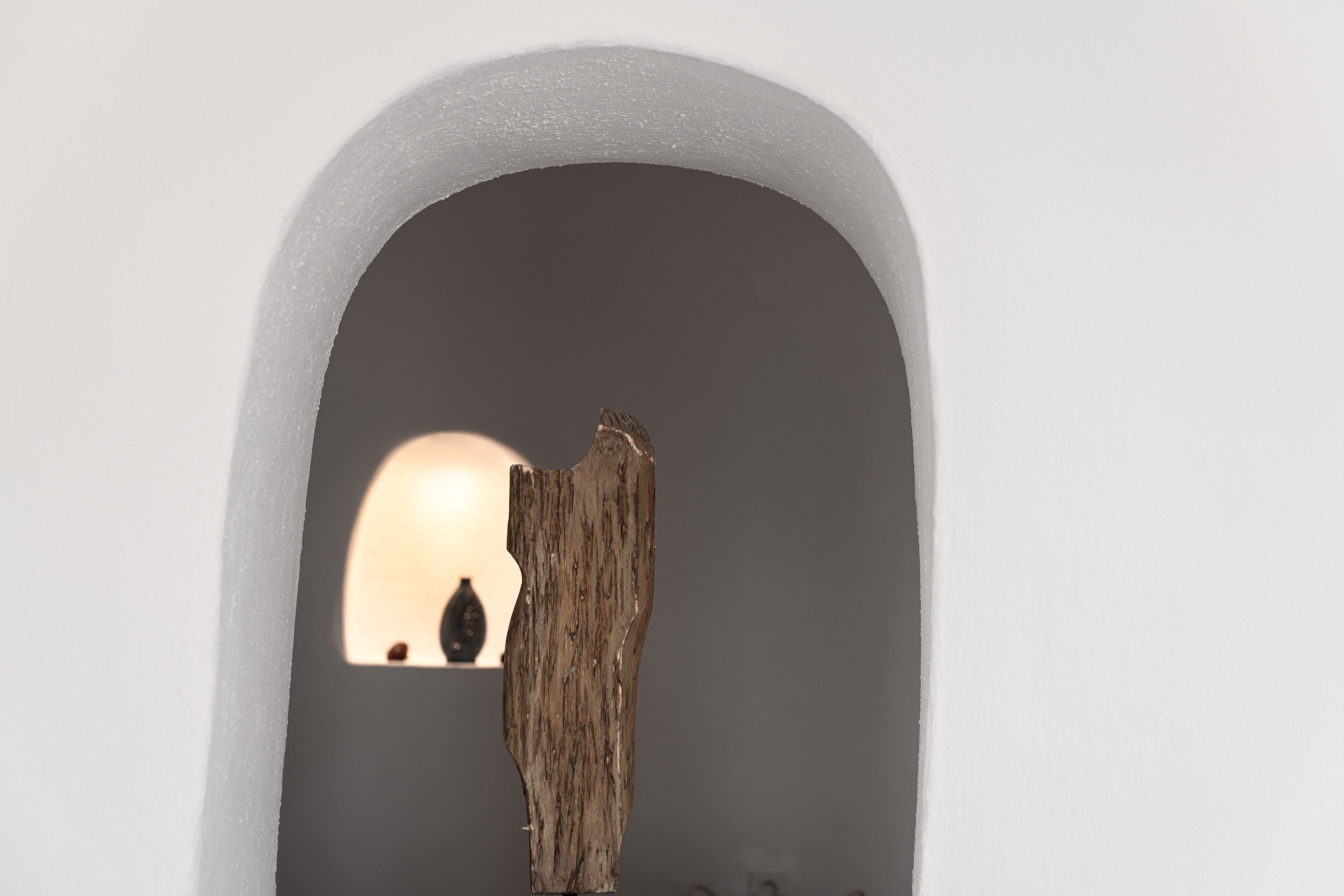 A wooden sculpture in a white arched niche.