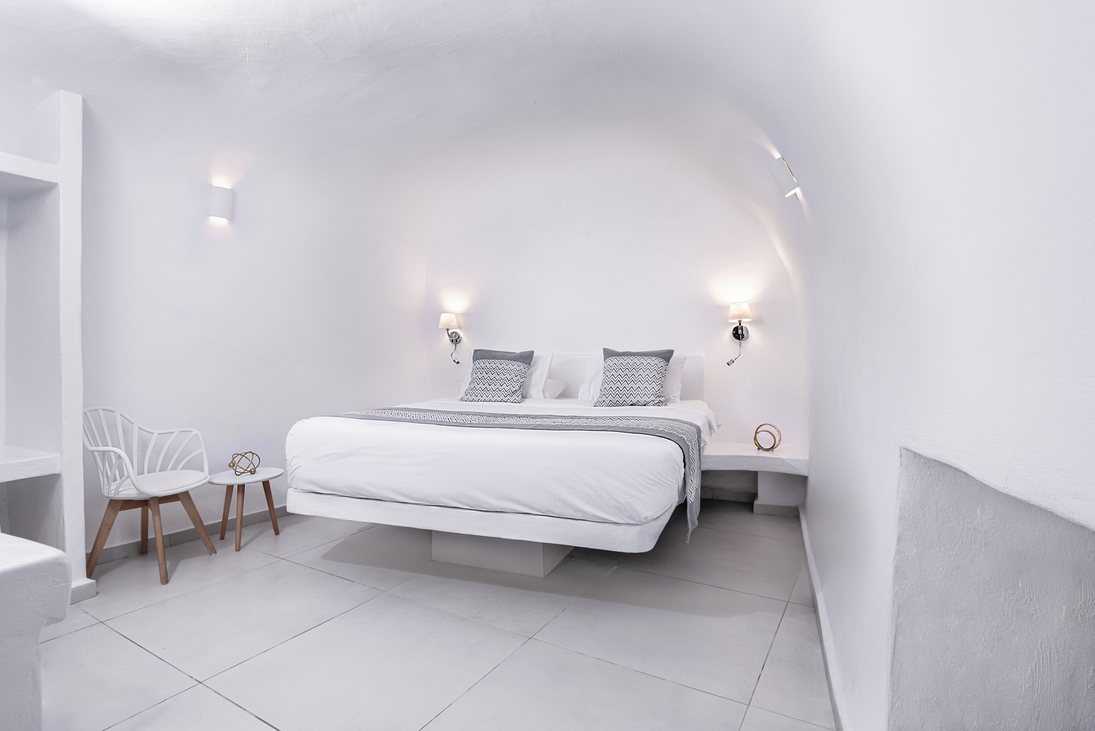 Une chambre à coucher au style minimaliste, avec un lit, des tables de chevet et une chaise.