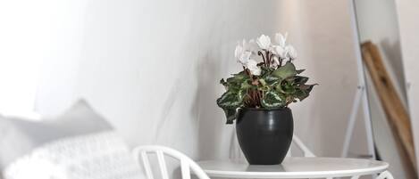 Una mesa blanca con una maceta negra llena de flores blancas.