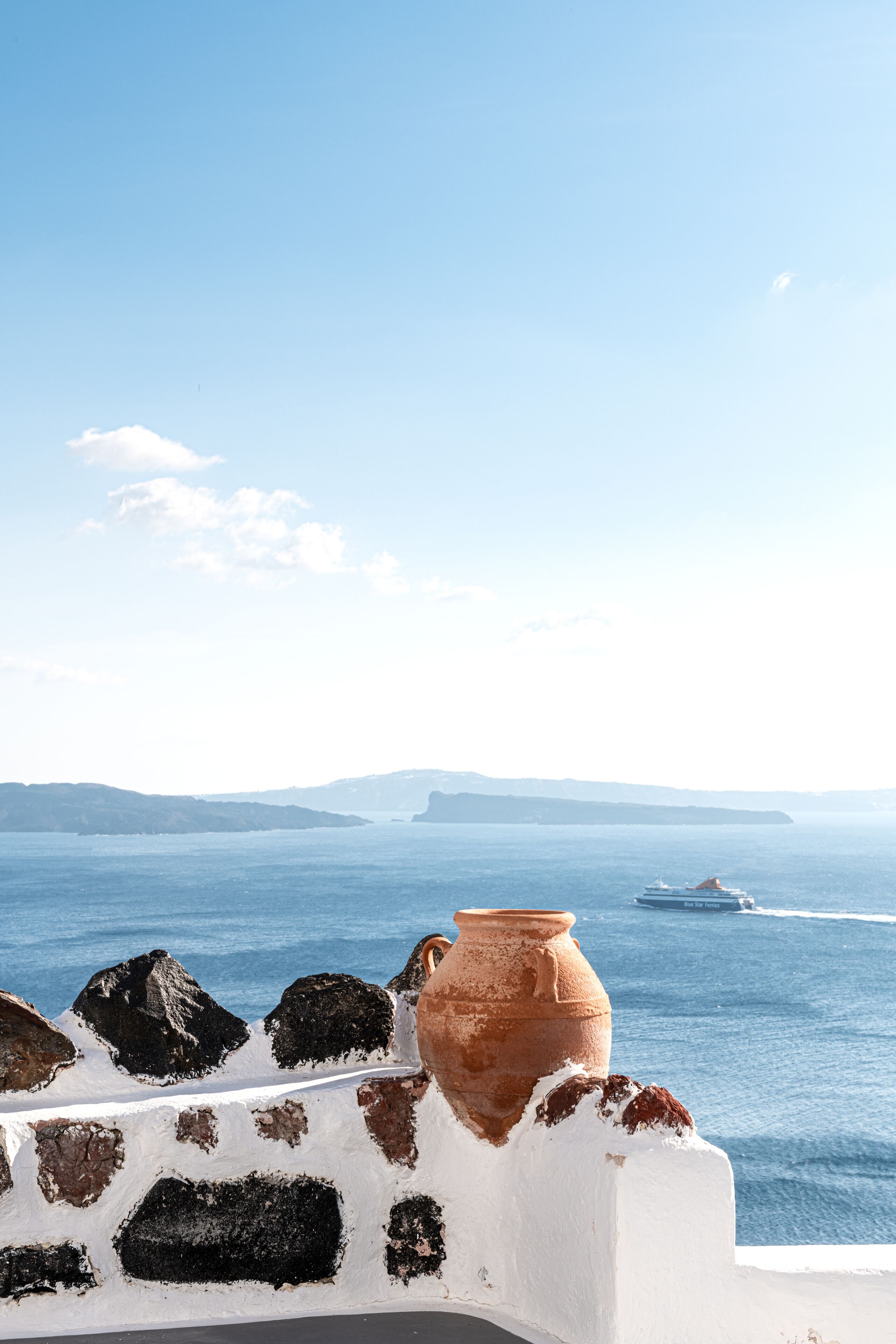 A coastal view with a white wall and a terracotta pot.