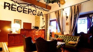 Un vestíbulo acogedor con una recepción, sillones de cuero y un sofá verde.