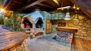 Una chimenea rústica de piedra con un banco de madera, un muro de piedra y lámparas colgantes.