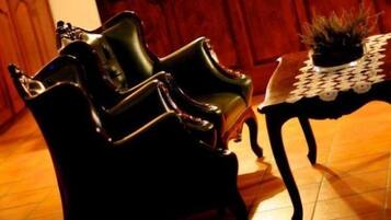 Una habitación con una silla de madera oscura y una pequeña mesa con un adorno encima.