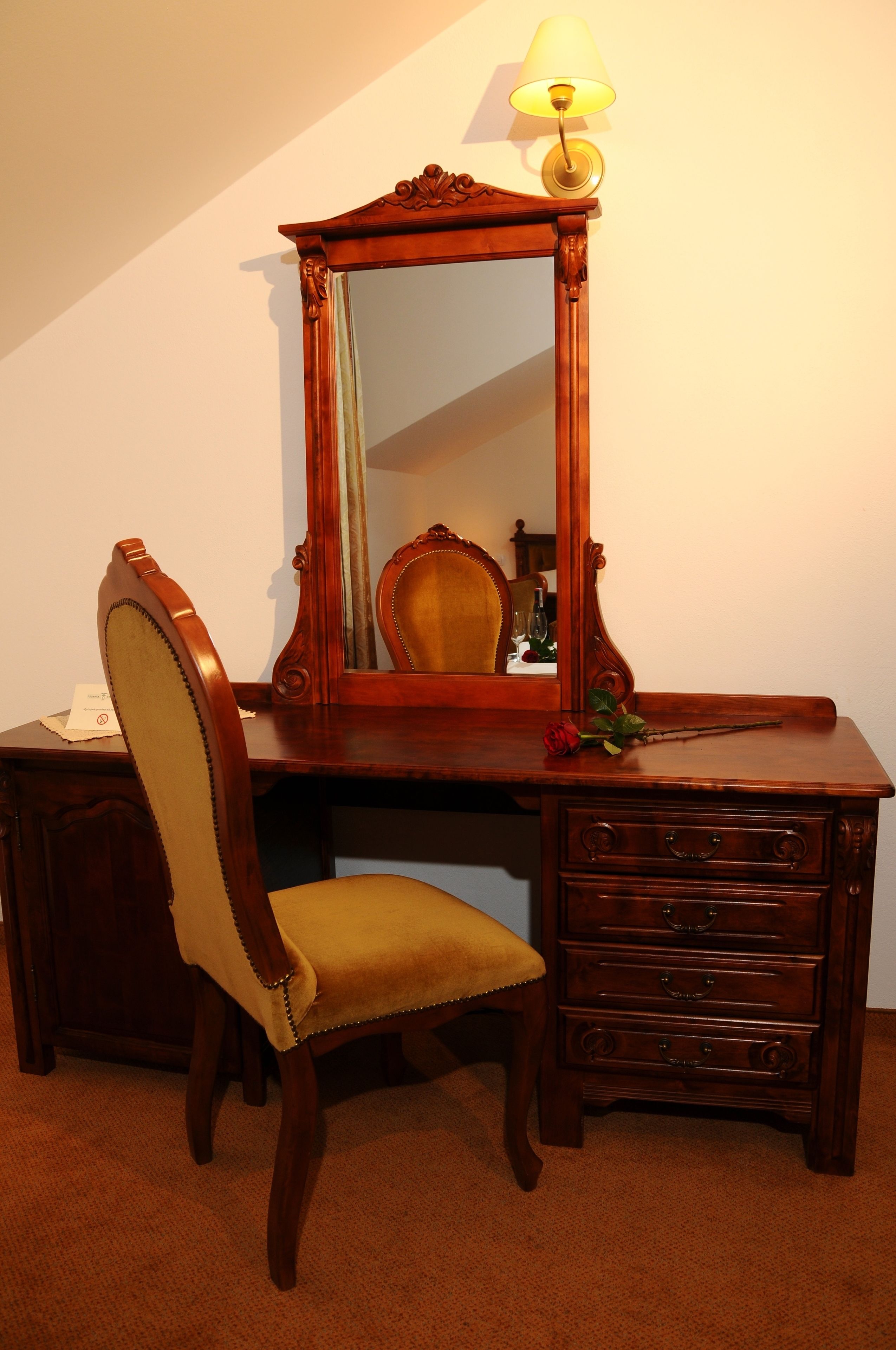 A wooden desk with a mirror, a chair, and a lamp.