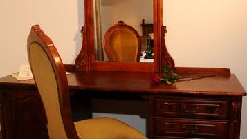 A wooden desk with a mirror, a chair, and a lamp.