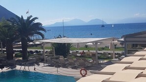 Un área de piscina con sillones de descanso y vista al mar.