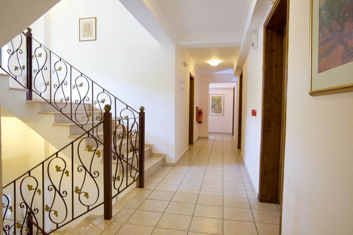 A hallway with a staircase featuring ornate metal railings and a tiled floor.