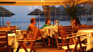Un restaurante con mobiliario de madera y amplias ventanas con vistas al mar.