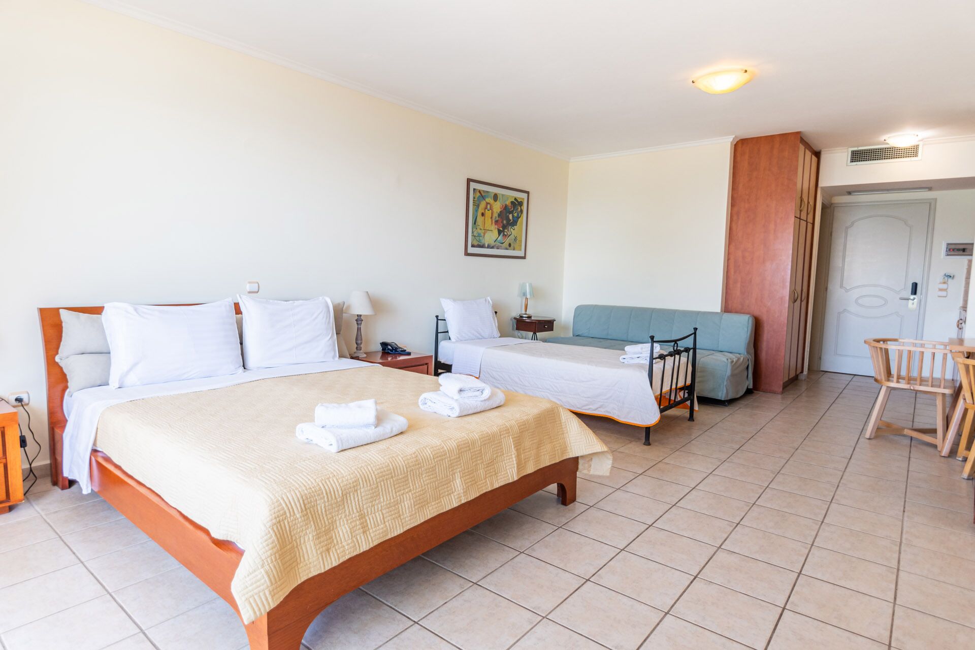 A hotel room with two beds, a sofa, a desk, and a chair.