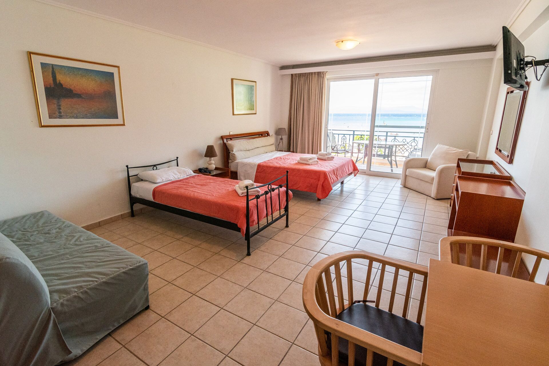 Une chambre d’hôtel avec deux lits, un canapé, un bureau et un balcon avec vue.