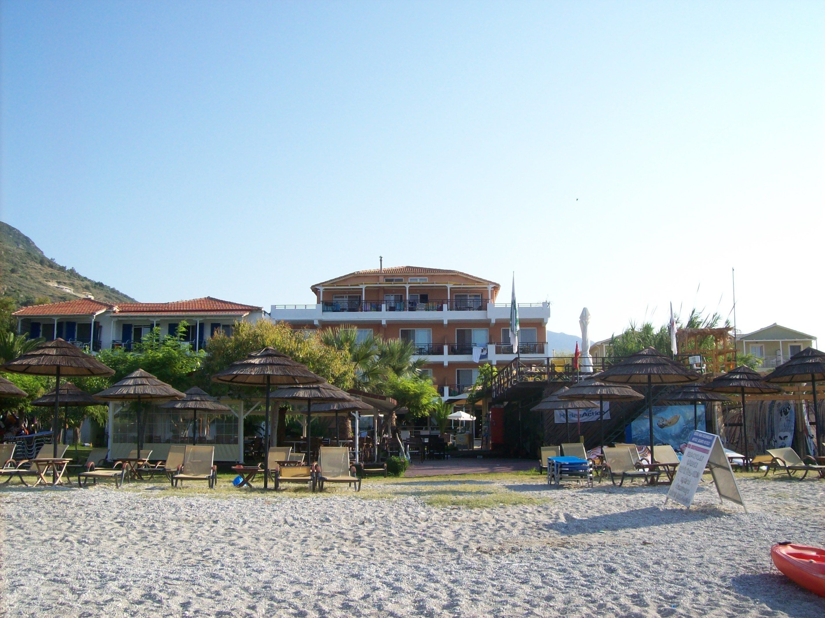 Un hotel frente a la playa con varios balcones, sillas y sombrillas.