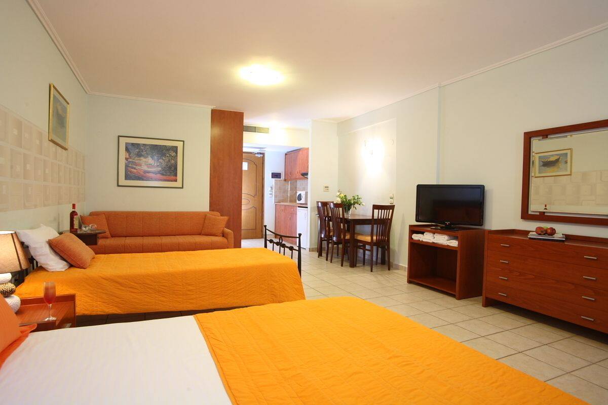 Habitación de hotel con dos camas, televisión, zona de comedor y baño.