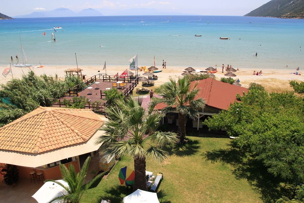 A beach resort with a pool area, palm trees, and a view of the sea.