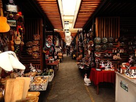 Mercado cubierto con puestos de madera que ofrecen diversos artículos como cerámica, textiles y juguetes.