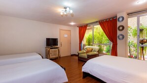 A hotel room with two beds, a television on a wooden cabinet, and a window with orange curtains. - Hotel Boutique Los Balcones (Cuenca)