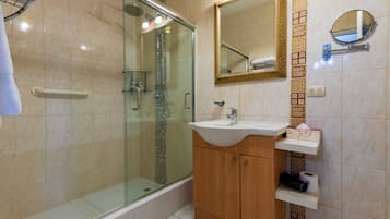 Un baño con cabina de ducha de vidrio, un lavabo, un espejo y un perchero para toallas.