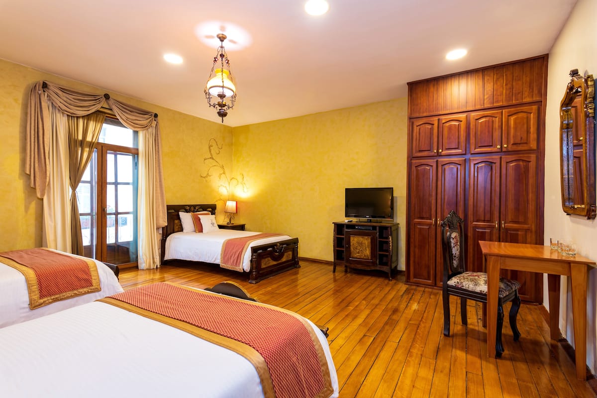 Una habitación de hotel con dos camas, televisión, armario de madera y escritorio con silla.
