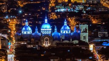 A night view of a cityscape with illuminated domed buildings, likely a cathedral or large church, surrounded by residential buildings and streets.