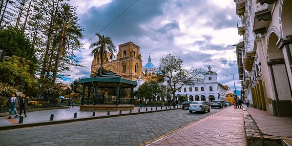 A cobblestone street with a gazebo, a church with a blue dome, and a white building with arches. - Hotel Boutique Los Balcones (Cuenca)