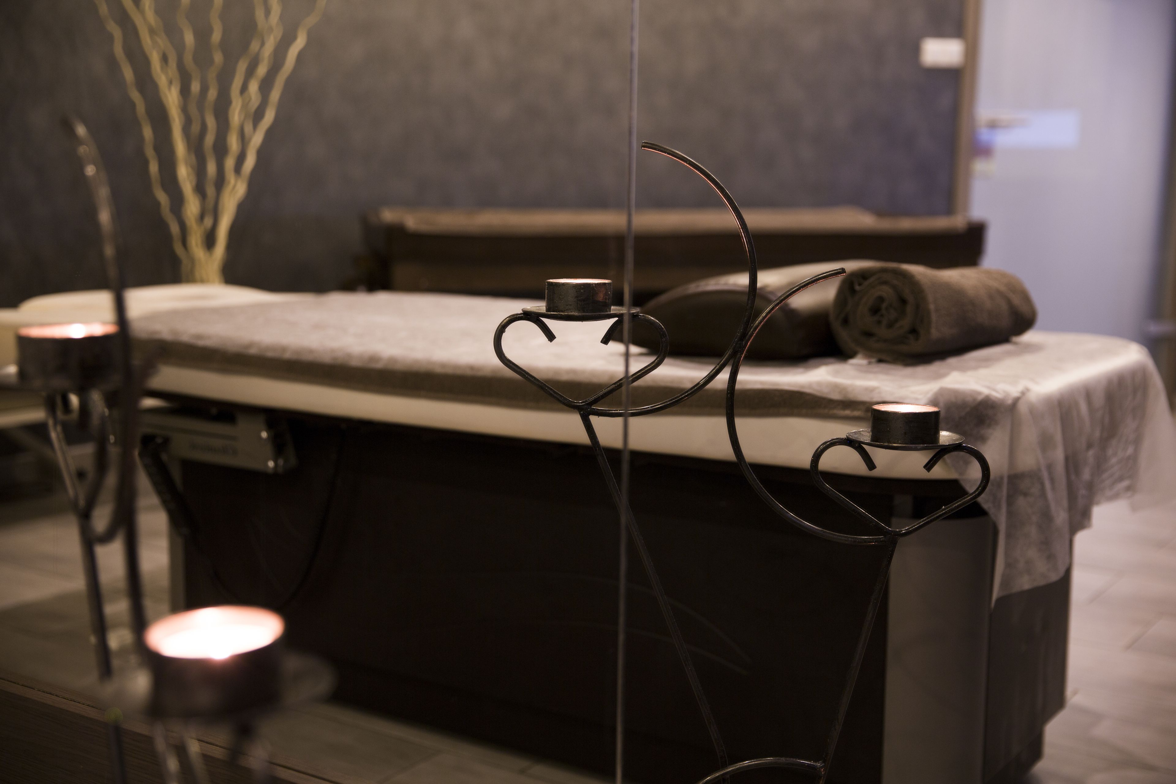 Et spa-rum med massagestol, stearinlys og en dekorativ plante.