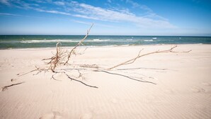 A sandy beach with a clear sky and calm sea. - Hotel Jantar (Ustka)