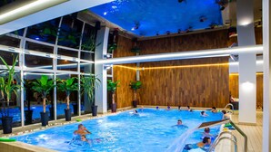 An indoor swimming pool with multiple lanes, surrounded by wooden walls and large windows. - Hotel Jantar (Ustka)