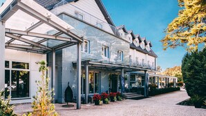 A modern hotel with a covered outdoor area, large windows, and a well-maintained garden. - Hotel Jantar (Ustka)