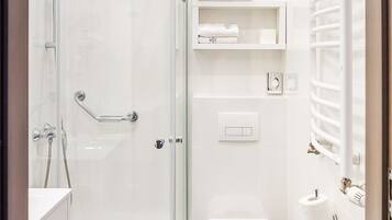 A modern bathroom with a glass-enclosed shower, a toilet, and a bathtub.