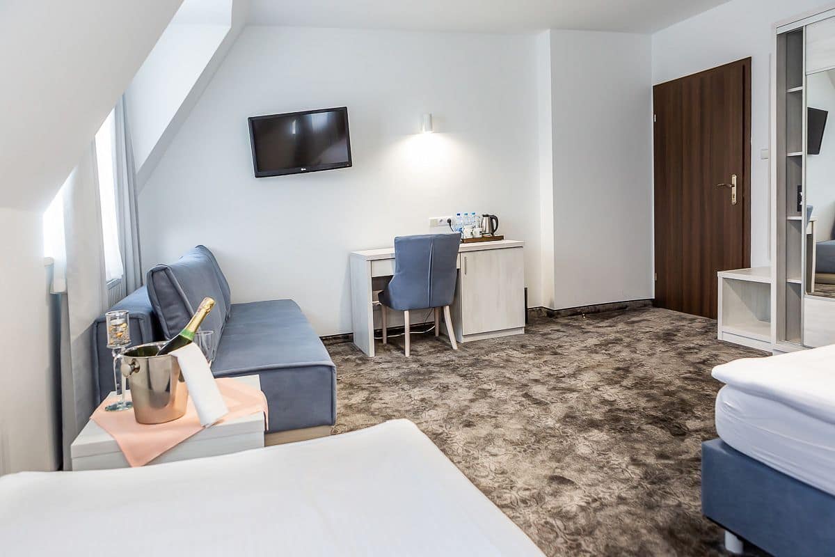 Une chambre d’hôtel moderne équipée d’un lit, d’un bureau, d’une chaise, d’une télévision et d’un mini-bar.