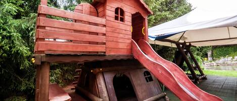 Una estructura de madera con un tobogán y una casita.