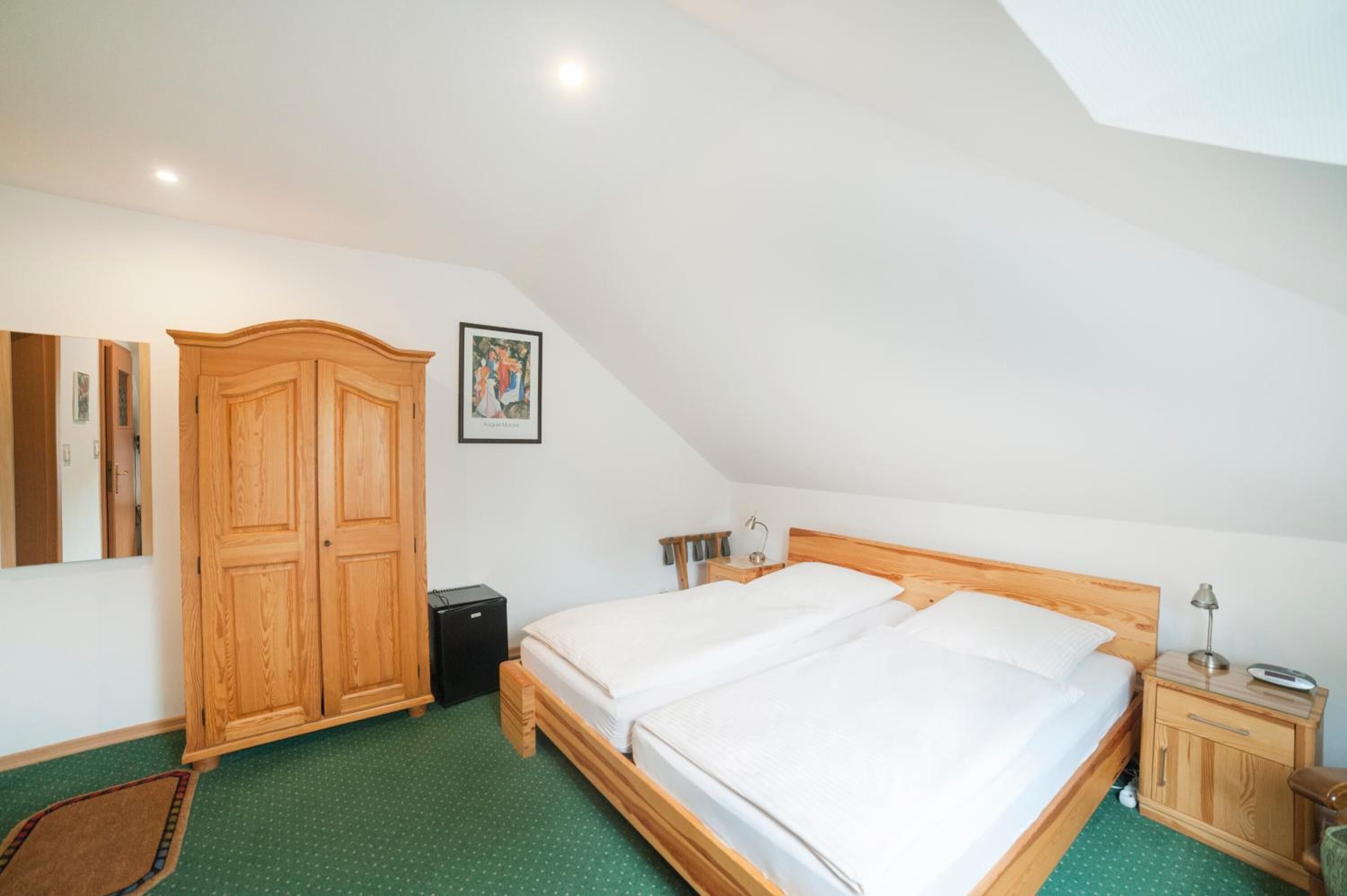 A bedroom with a large bed, a wardrobe, a bedside table, and a small cabinet.