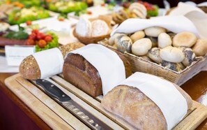 A variety of breads and pastries displayed on a wooden board. - Bukowy Park Hotel Medical Spa (Polanica-Zdroj)
