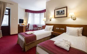 A hotel room with two beds, a desk, a chair, a TV, and a framed picture on the wall. - Bukowy Park Hotel Medical Spa (Polanica-Zdroj)