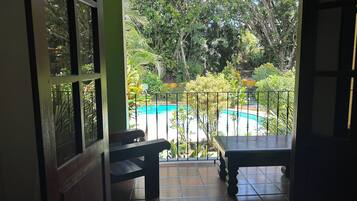 Une vue depuis un balcon donnant sur une piscine, le tout entouré d’une végétation luxuriante.