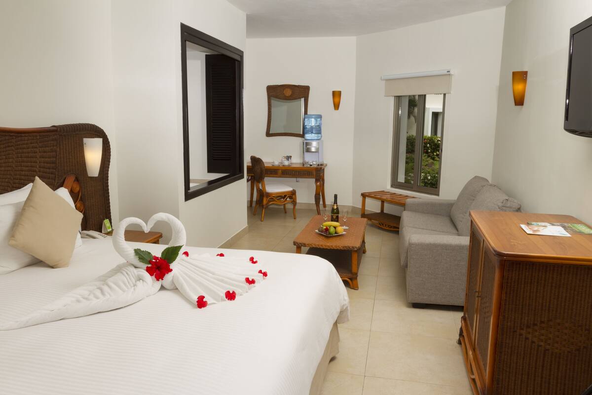 Una habitación de hotel con cama, sofá, escritorio y televisión.
