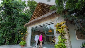 A building with a glass entrance, surrounded by lush greenery. -  Select Club at Sandos Caracol All Inclusive - Adults Only Area (Playa del Carmen)