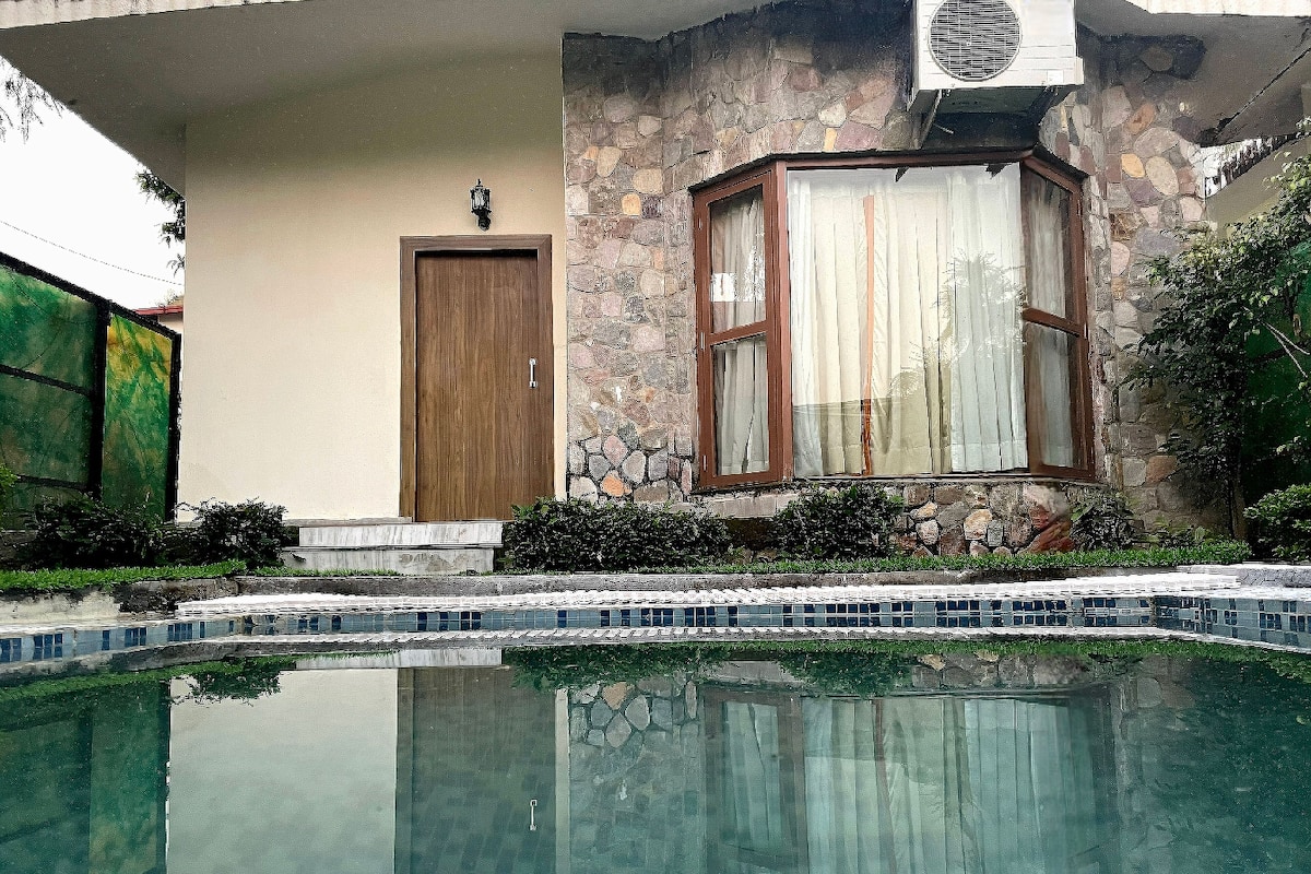 A swimming pool with a stone wall and a wooden door in the background.