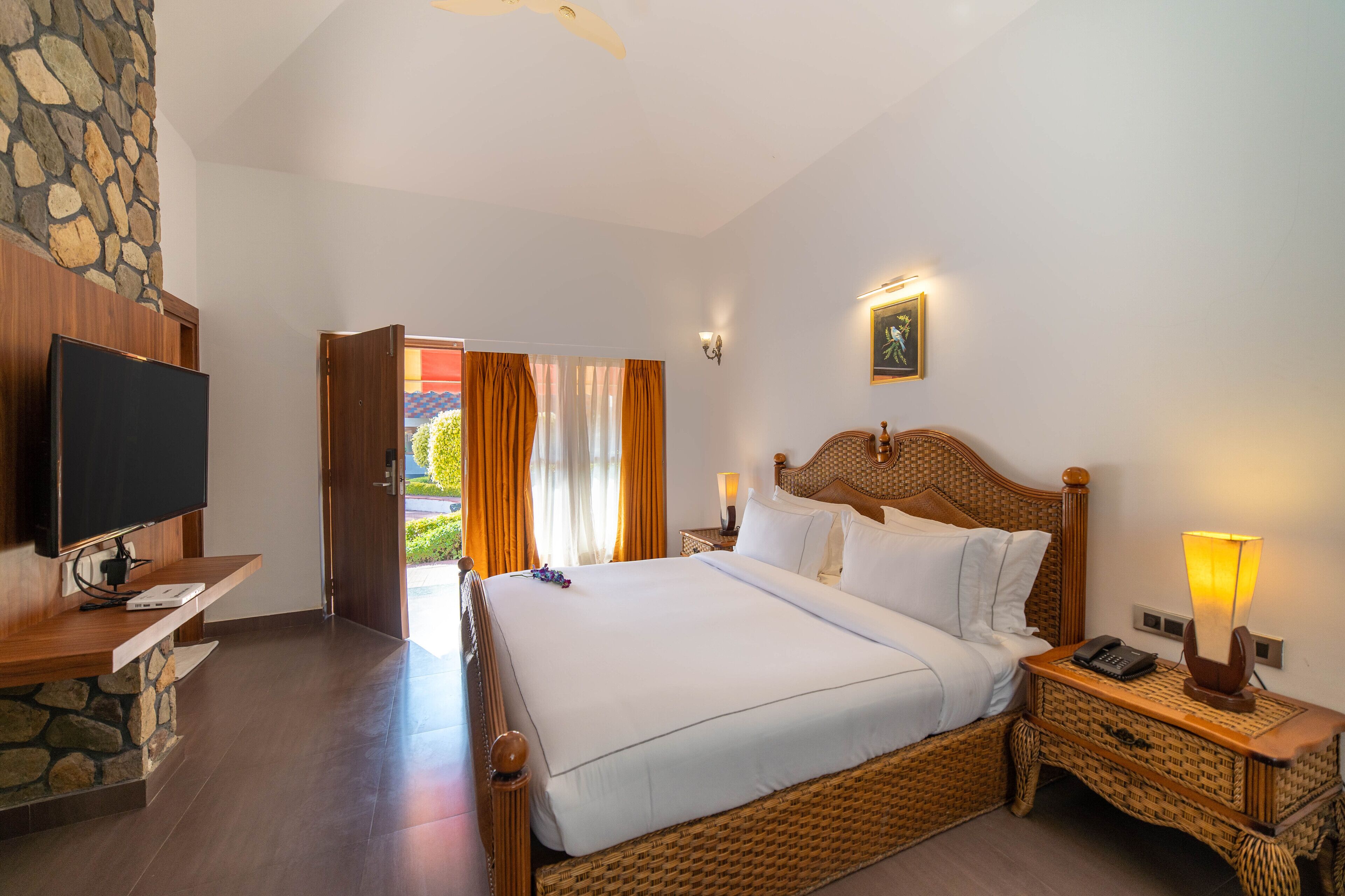 Un dormitorio con una cama grande, televisión, pared de piedra y vistas al exterior.