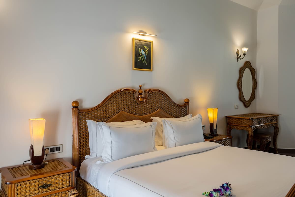 A neatly made bed with white linens, a wooden headboard, and two bedside lamps.