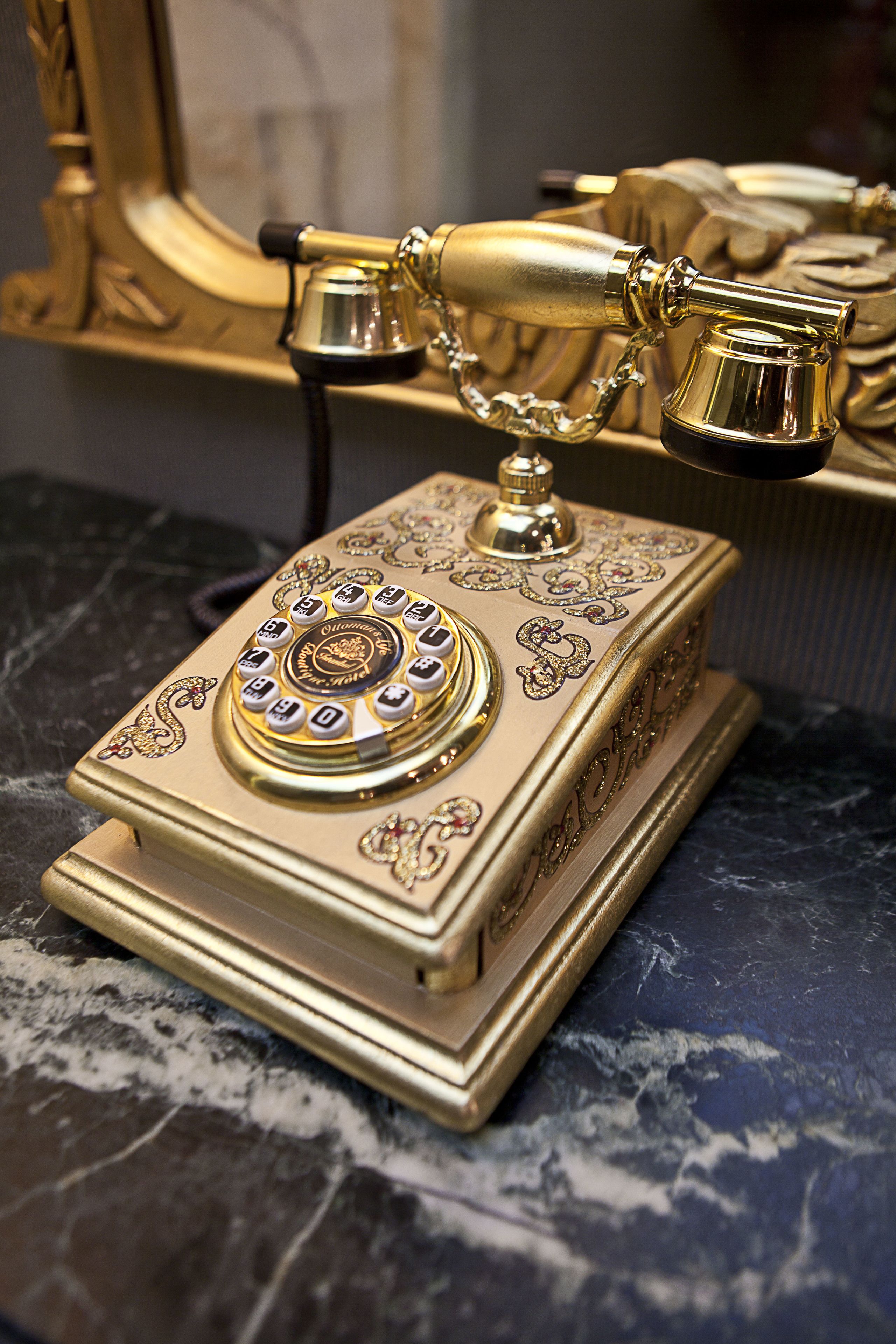 A vintage gold telephone on a marble surface.